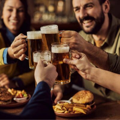Close-up of group of friends toasting with beer while eating in a pub
