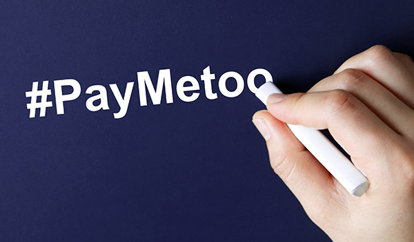 The hand writing text #PayMeToo in white chalk. A campaign to close the gender pay gap.